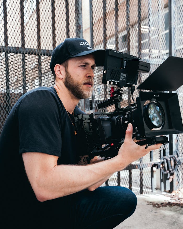 Menus A male cinematographer operates a high-end camera outdoors, capturing footage.